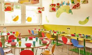 Der Raum zum Essen in der Kita kinderzimmer Unnenland, bunte Stühle stehen an bunten Tischen, an der Wand ist Gemüse und Obst an die Wand gemalt