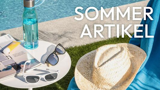 Am Rand eines Swimmingpools liegen Sonnenbrillen, eine Zeitschrift und ein Strohhut