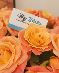 Eine Visitenkarte von Miry Waxing steckt in einem Strauß orangefarbener Rosen