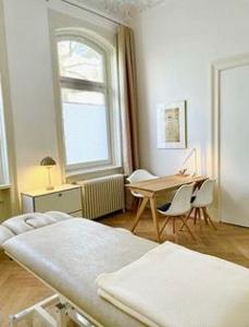 Ein Raum mit runden Fenstern und Holzfußboden, einem kleinen Tisch mit Stuhl und einer Liege