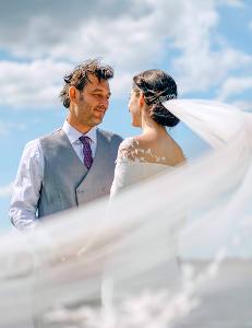 Ein Brautpaar unter blauem Himmel lächelt sich an