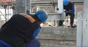 Zwei Männer arbeiten an einer Stahlkonstruktion auf einer Baustelle