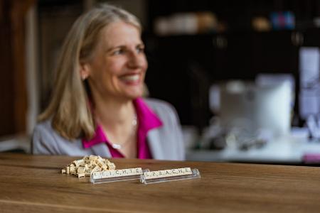 Ursula Finnern-Seul sitzt hinter einem Tisch auf dem Scrabble Buchstaben die Worte leichte Sprache bilden