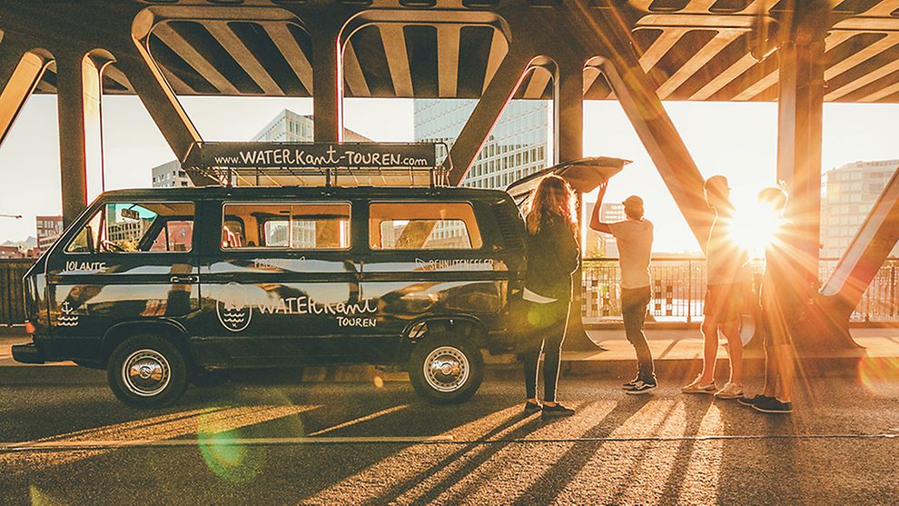  Ein VW Bulli auf einer Brücke, Sonnenschein im Hintergrund