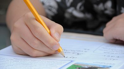  Kinderhand schreibt mit Bleistift auf Papier