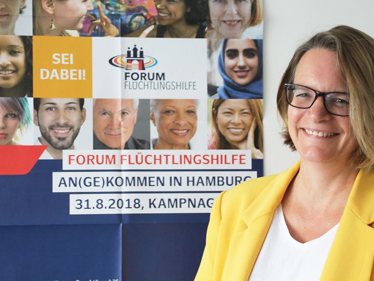  Frau Winterscheid steht vor dem Plakat zum Forum Flüchtlingshilfe 2018
