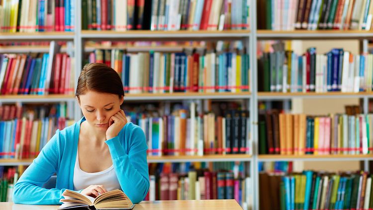  Motivbild Studium: junge Frau vor Bücherregal