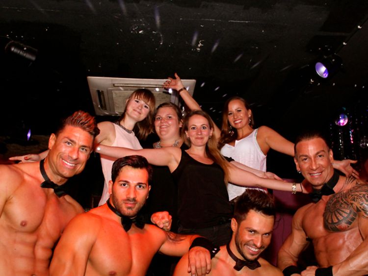  vier Stripper und eine Frauen-Gruppe, die einen Junggesellinnenabschied feiert