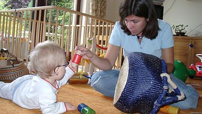  Eine Therapeutin spielt mit einem Krabbelkind