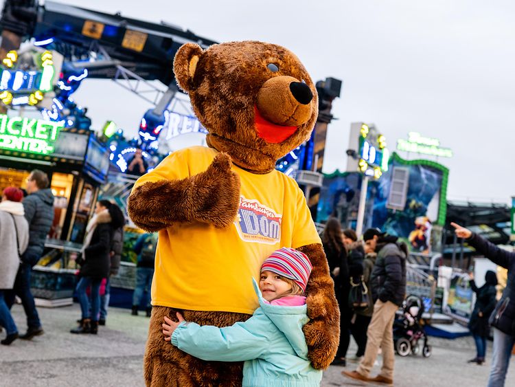  DOM-Bär wird von einem Kind umarmt. 