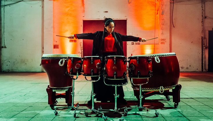 Eine chinesische Musikerin breitet die Arme aus, um mit den Schlegeln zu trommeln