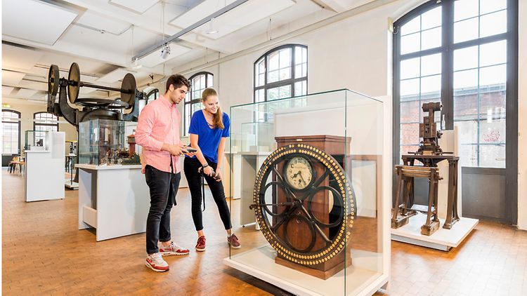  ein junges Paar betrachtet die Arbeiterkontrolluhr im Museum der Arbeit