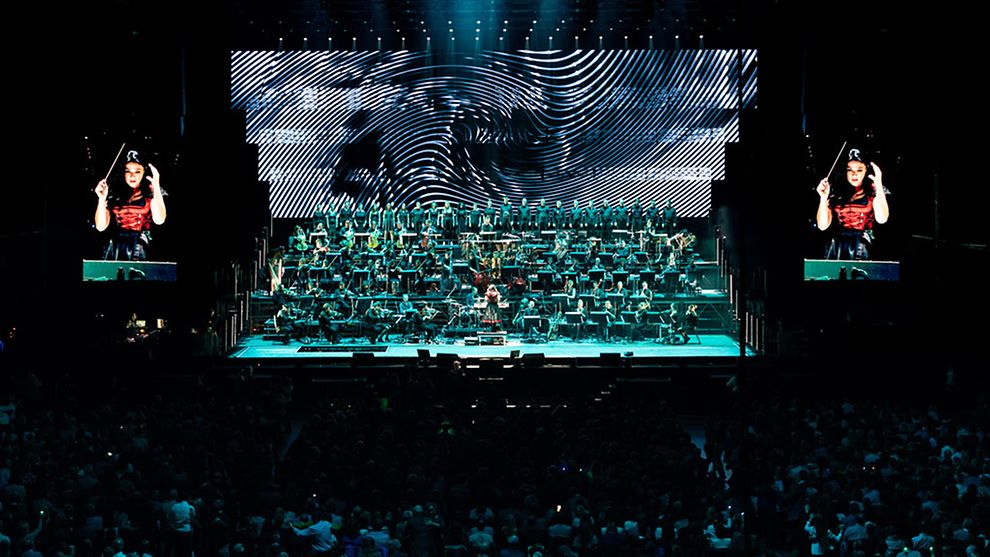 Aufnahme des Antwerp Philharmonic Orchestra auf einer großen Bühne. Das Geschehen wird auf zwei großen Leinwänden übertragen.