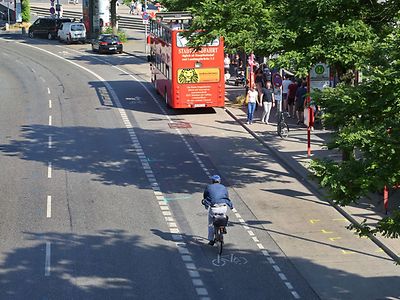  Ein Radfahrer fährt auf dem Fahrradweg an den Landungsbrücken. Ein roter Doppeldeckerbus steht an der Bushaltestelle.