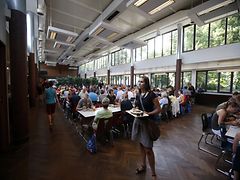  Blick in die Uni Mensa Hamburg, in dem gerade Menschen an den Tischen sitzen und essen.