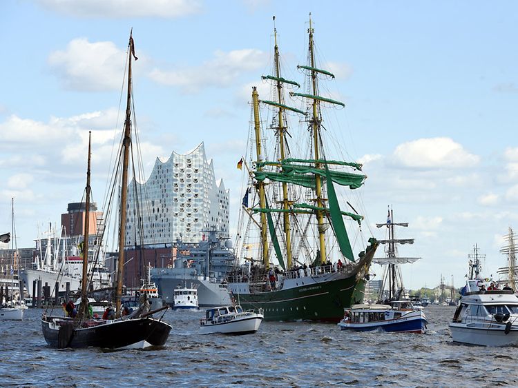  Mehrere Schiffe, größere und kleinere, Segelschiffe und Motorboote, fahren auf der Elbe vor der Elbphilharmonie.