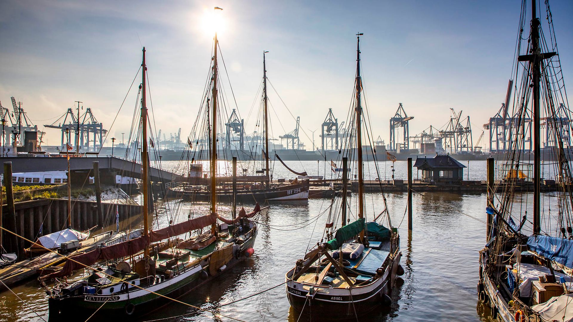  Alte Schiffe liegen im Wasser, im Hintergrund moderne Hafenkrane