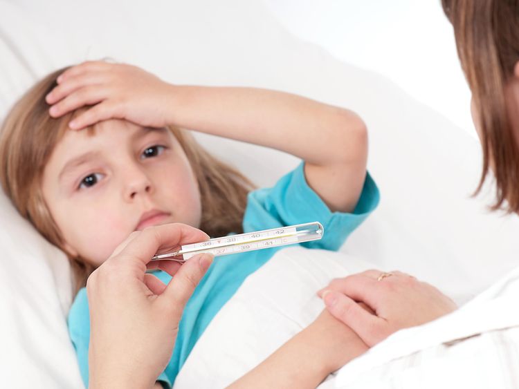  Fiebermessen bei einem Kind, das im Bett liegt