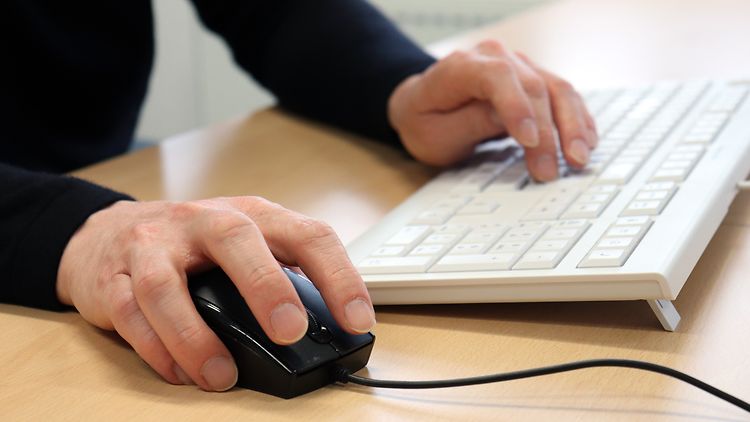  Eine Maus und Tastatur wird von zwei Händen bedient.