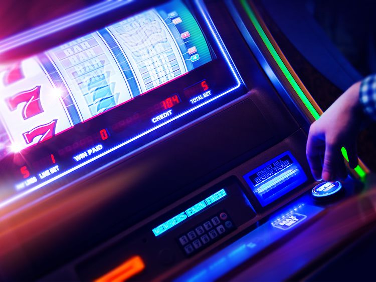  Eine Person drückt einen Schalter auf einem Spielautomaten