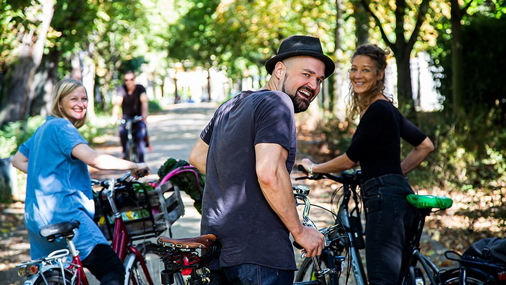 drei Personen mit Fahrrädern lächeln in die Kamera