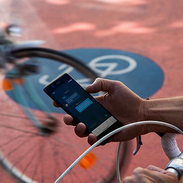  Fahrradweg im Hintergrund, Handy in einer Hand