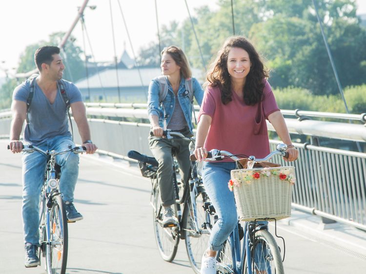  Drei Menschen fahren fröhlich mit dem Rad auf der Straße