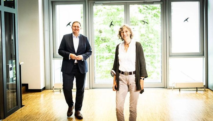 Kultursenator Carsten Brosda und NDR-Moderatorin Katja Weise laufen einen Flur entlang