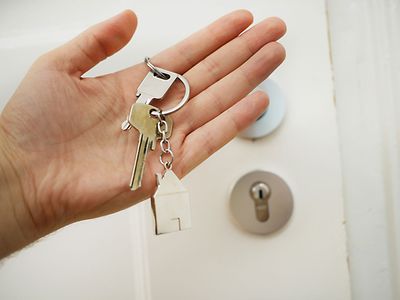  Hand mit Schlüsselbund vor einer weißen Haustür