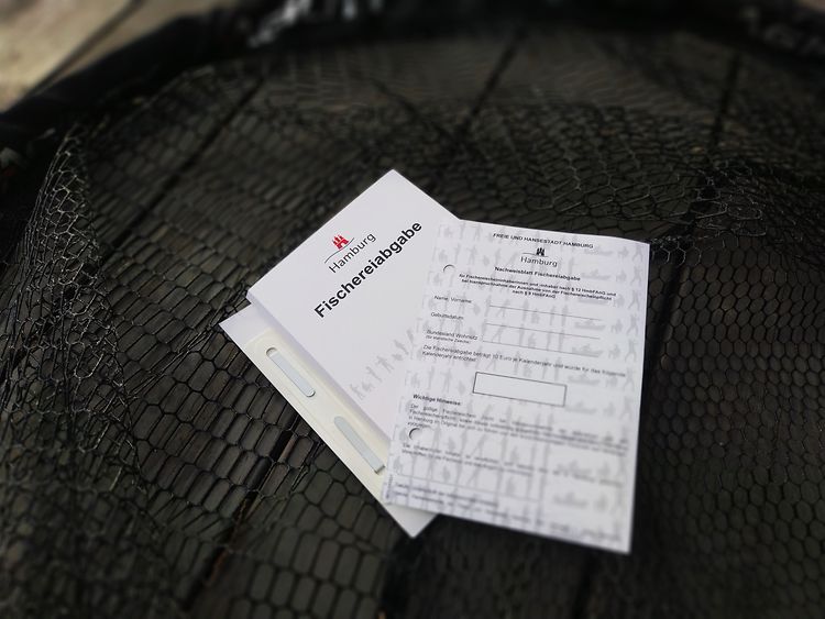  Nachweiszettel der Fischereiabgabe liegen auf einem Kescher.