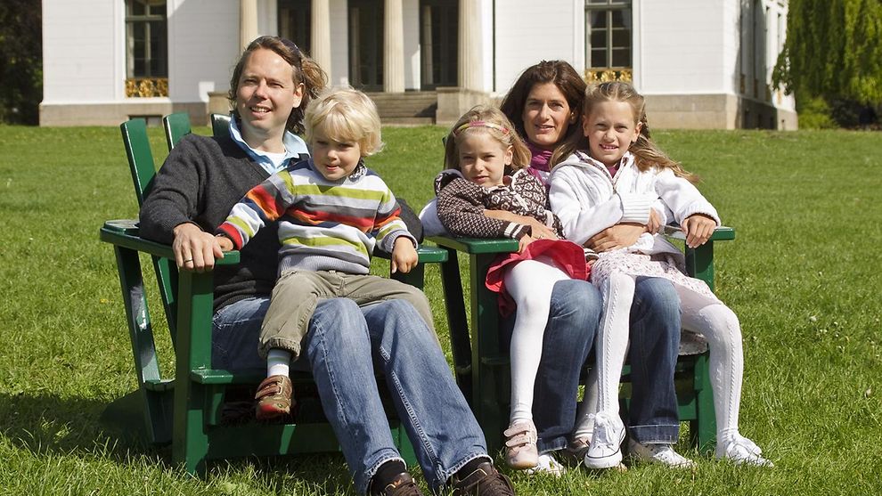 Eine Familie sitzt auf grünen Holzstühlen im Jenischpark