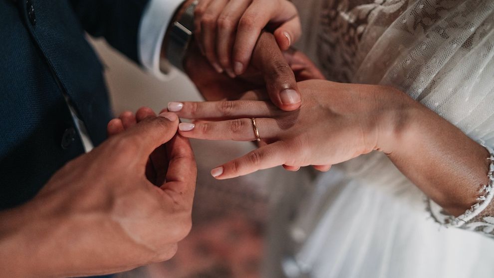Ein Mann streift einer Frau einen Ring über den Finger.