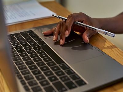  Eine Hand bedient eine Laptoptastatur und hält dabei einen Stift.