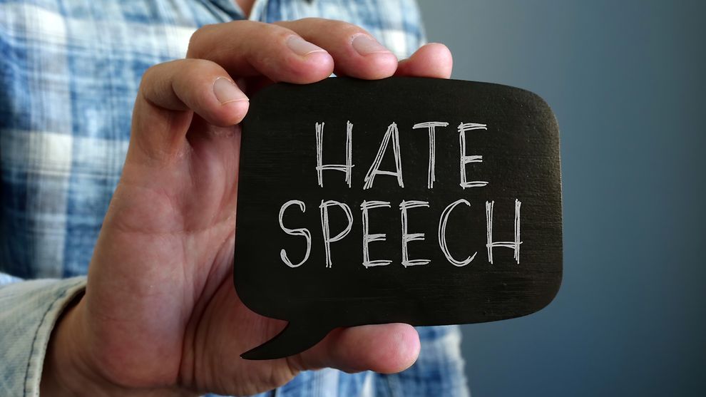 Ein Mann hält ein Schild, auf dem die Wörter Hate Speech stehen.