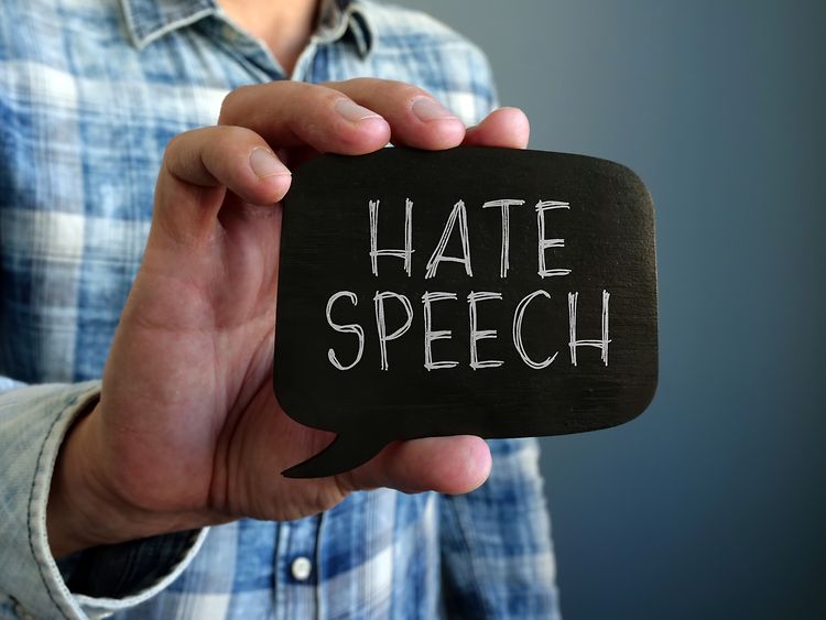  Ein Mann hält ein Schild, auf dem die Wörter Hate Speech stehen.