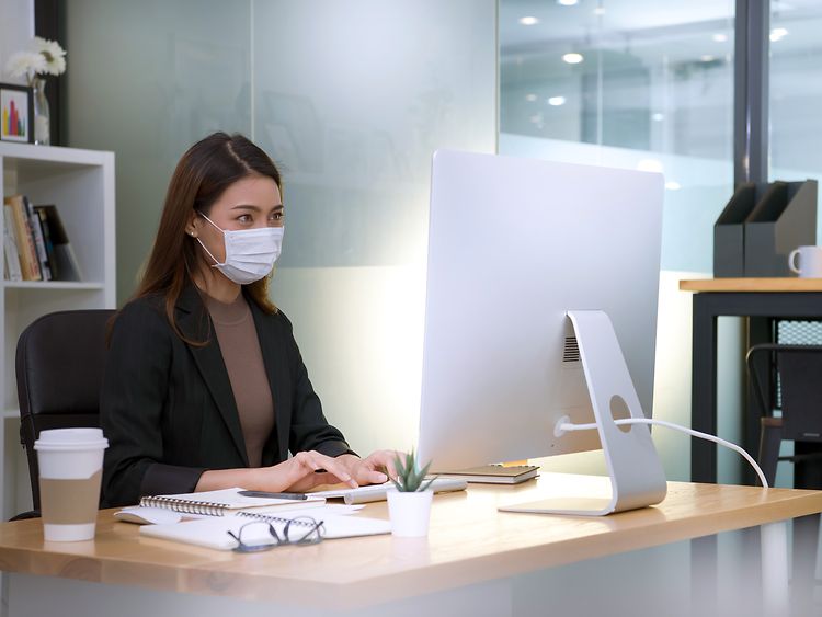  Eine Frauen trägt eine Maske am Arbeitsplatz.