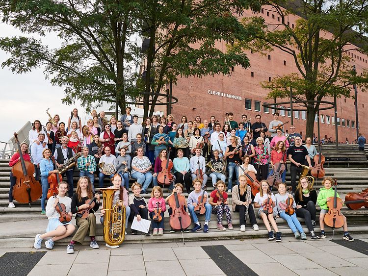  Das Familienorchester zeigt sich im Gruppenbild auf der Freitreppe zum Kleiner Saal in der Elbphilharmonie. Alle sind mit dabei, Großeltern, Eltern, Kinder - eine fröhliche Musikergroßfamilie!