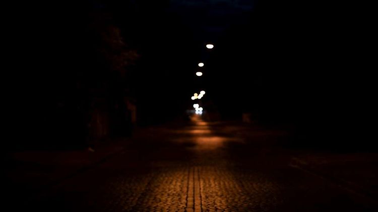  Ein Weg ist in der Dunkelheit mit schwachem Laternenlicht beleuchtet.