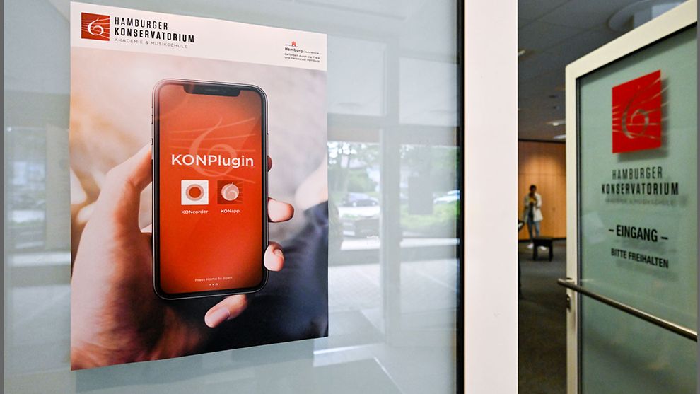 Ein Plakat mit dem Bild eines Smartphones vor dem Eingang des Hamburger Konservatoriums