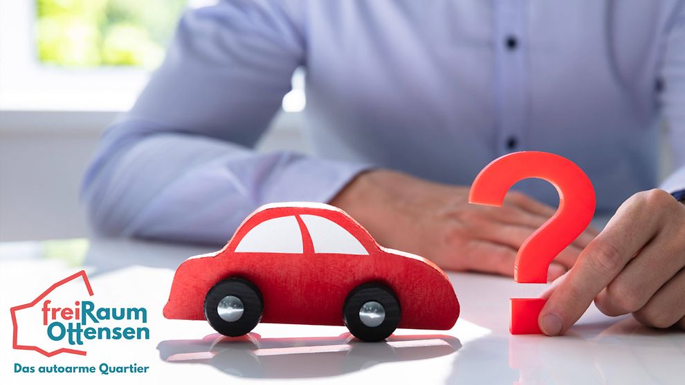 Ein Mensch hält ein rotes Fragezeichen in der Hand. Davor sieht man das kleine Modell eines roten Autos. Daneben steht freiRaum Ottensen - Das autoarme Quartier.