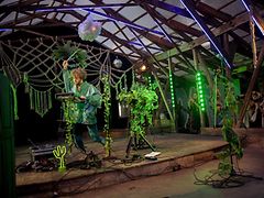  Der Kölner Künstler Moglii bei seinem Auftritt beim Fast ein MS Dockville. Die Bühne ist grün beleuchtet und mit Pflanzen geschmückt.