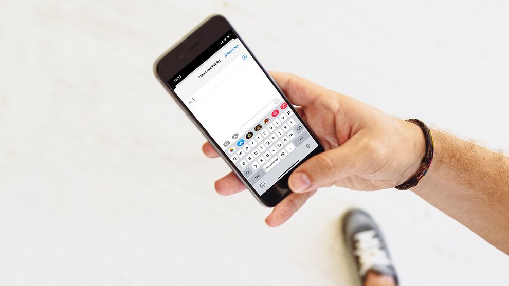  Abbildung einer Hand die eine Kurztextnachricht (SMS) in ein Mobiltelefon eintippt