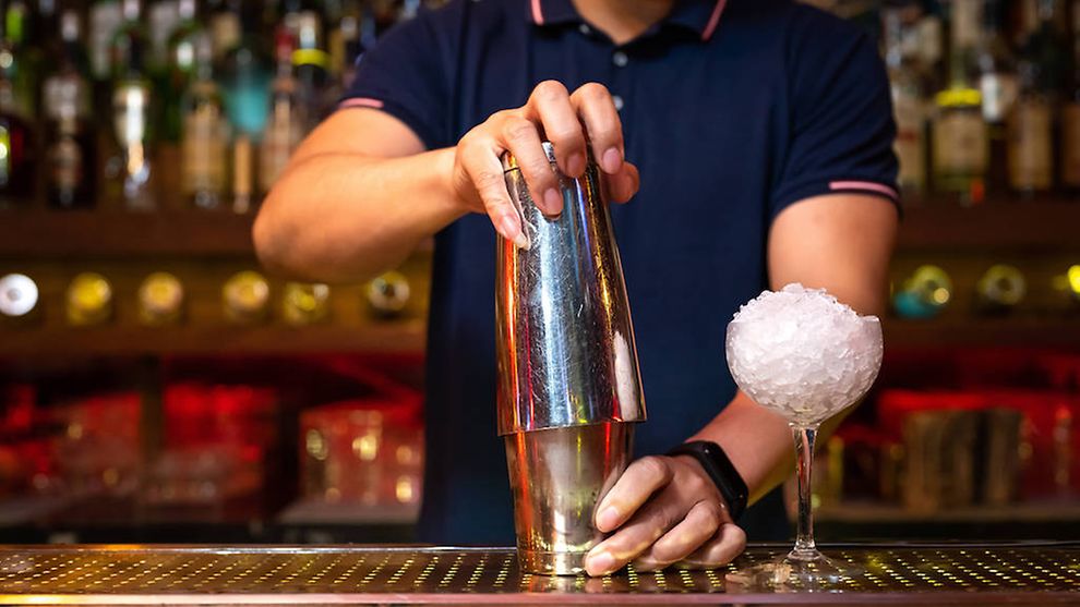 Ein Barkeeper bereitet einen Cocktail mit Eis zu.