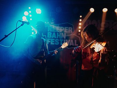  Ein Musiker an der Gitarre und eine Musikerin an der Geige auf einer Bühne beim Reeperbahnfestival