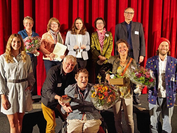  Gruppenfoto mit elf Personen, davon einige mit Blumensträußen in der Hand