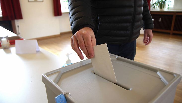 Eine Person wirft ihren Stimmzettel in eine Wahlurne.