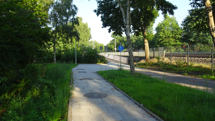  Ein gepflasterter Fußweg mit eingebauter Versickerungsanlage und Gullideckeln.