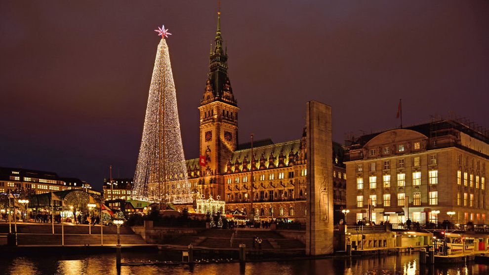  Das Hamburger Rathaus bei Nacht zur Weihnachtszeit mit einem Weihnachtsbaum aus Lichtern vorne stehend.