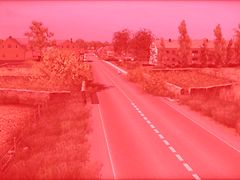  Eine Fotografie einer Straße mit Grünstreifen an der Seite aus der Vogelperspektive mit einem Rotfilter überlegt.