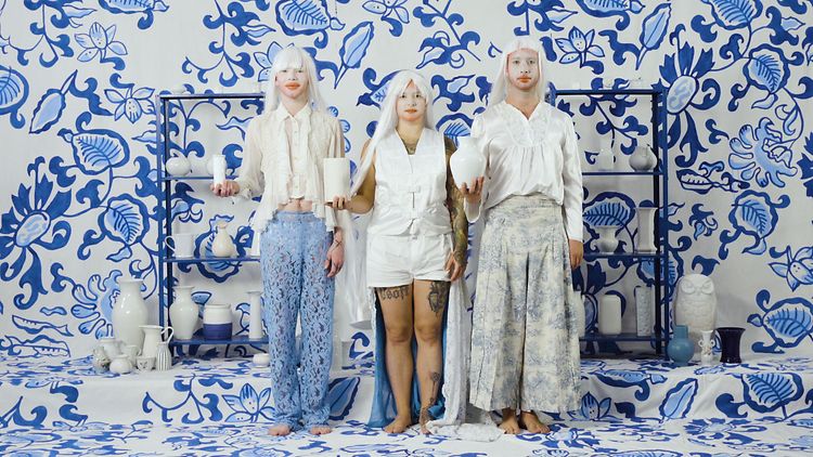  Drei Personen mit weißen Perücken vor einer Wand mit blauem Porzellanmuster